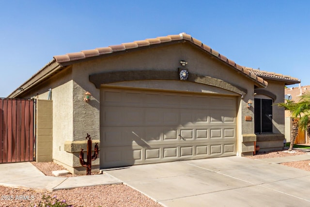 view of front of property featuring concrete driveway, a tiled roof, an attached garage, fence, and stucco siding