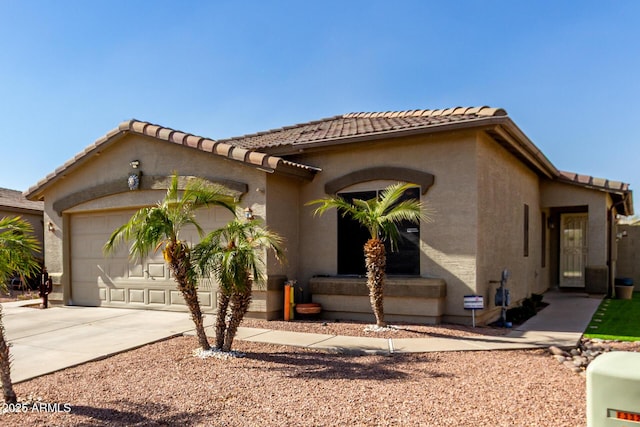 mediterranean / spanish-style home featuring a garage, concrete driveway, a tile roof, and stucco siding