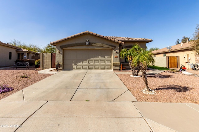 view of front of property featuring a garage, fence, a tile roof, driveway, and stucco siding