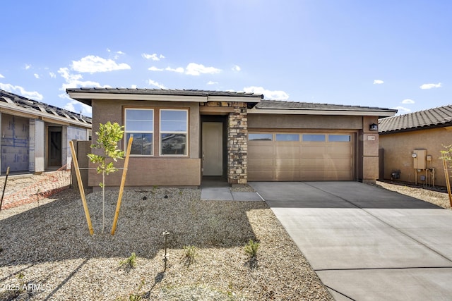 prairie-style home featuring concrete driveway, a tiled roof, a garage, and stucco siding