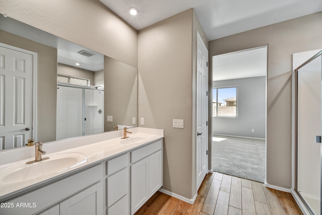 bathroom featuring a stall shower, wood finished floors, visible vents, and a sink