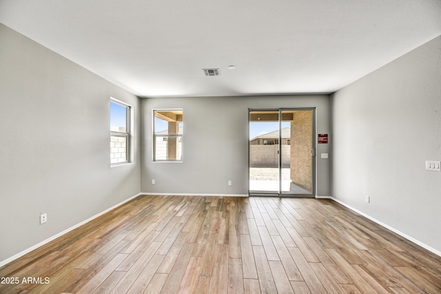 unfurnished room featuring wood finished floors, visible vents, and baseboards