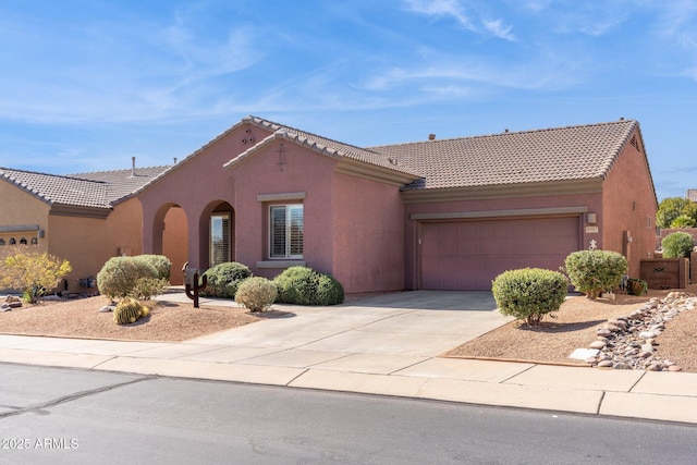 view of front of property featuring concrete driveway, a tiled roof, an attached garage, and stucco siding