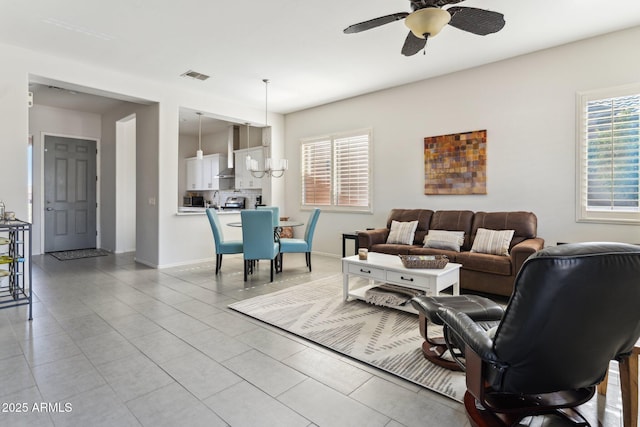 living room featuring light tile patterned floors, baseboards, visible vents, and ceiling fan