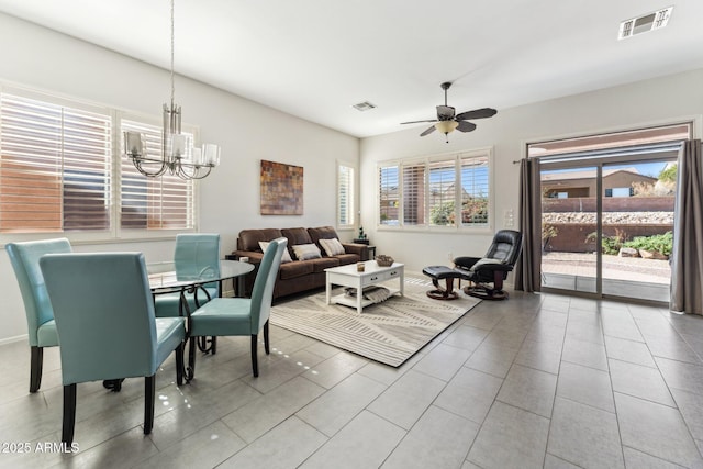 tiled dining area with ceiling fan with notable chandelier and visible vents