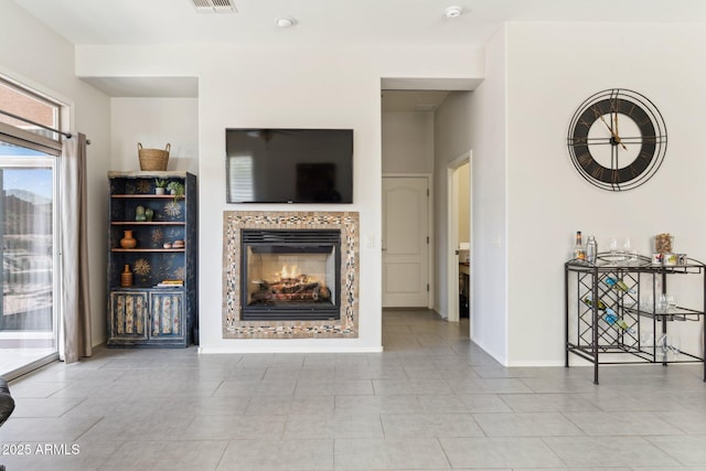 living area featuring a fireplace, visible vents, and baseboards