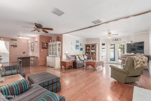 living room with crown molding, french doors, and light hardwood / wood-style flooring