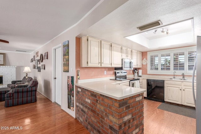 kitchen with white cabinets, sink, light wood-type flooring, appliances with stainless steel finishes, and kitchen peninsula