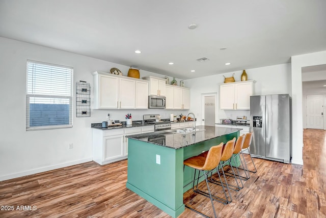 kitchen with sink, an island with sink, white cabinets, and appliances with stainless steel finishes