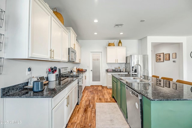 kitchen featuring appliances with stainless steel finishes, sink, light wood-type flooring, and white cabinets