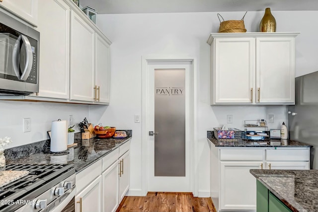 kitchen with dark stone countertops, light hardwood / wood-style flooring, and white cabinets