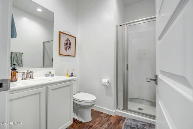 bathroom with hardwood / wood-style flooring, vanity, toilet, and a shower with door