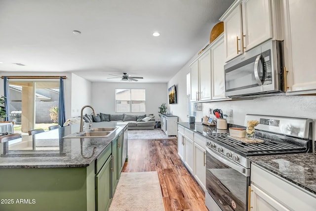 kitchen with white cabinetry, green cabinetry, appliances with stainless steel finishes, and sink