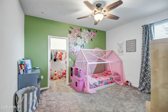 bedroom with a spacious closet, light colored carpet, and ceiling fan