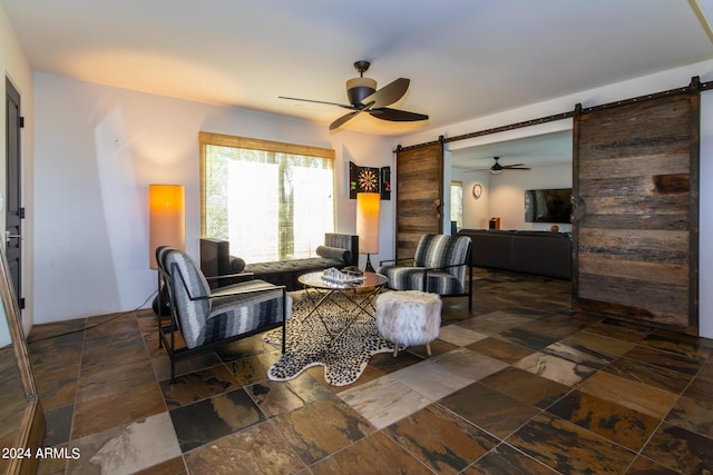 living room with ceiling fan and a barn door