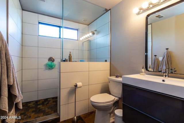 bathroom featuring vanity, tiled shower, and toilet