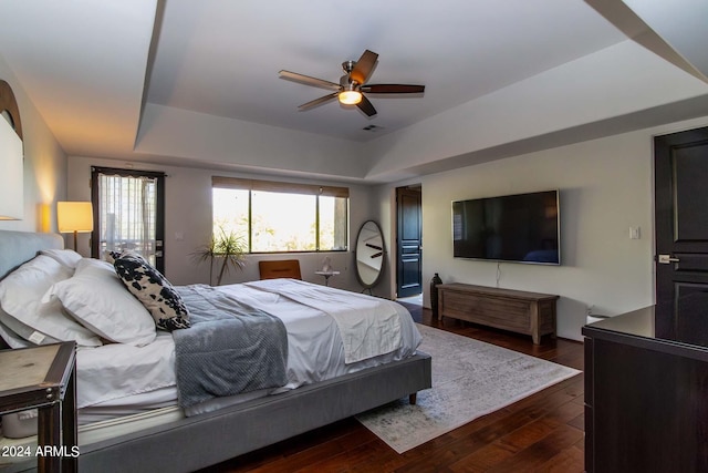 bedroom featuring dark hardwood / wood-style flooring, a raised ceiling, and ceiling fan