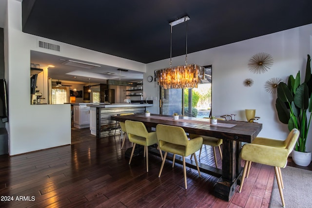 dining area with dark wood-type flooring and a notable chandelier