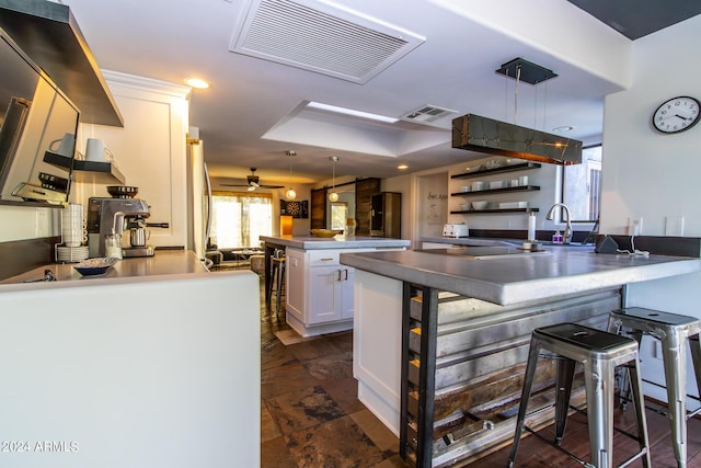 kitchen featuring decorative light fixtures, white cabinetry, a kitchen breakfast bar, ceiling fan, and kitchen peninsula