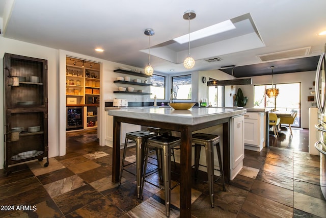 kitchen with white cabinetry, plenty of natural light, a kitchen bar, and decorative light fixtures