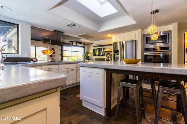 kitchen with sink, white cabinetry, decorative light fixtures, a raised ceiling, and stainless steel appliances