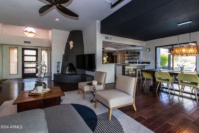 living room with dark wood-type flooring, ceiling fan, a fireplace, and sink