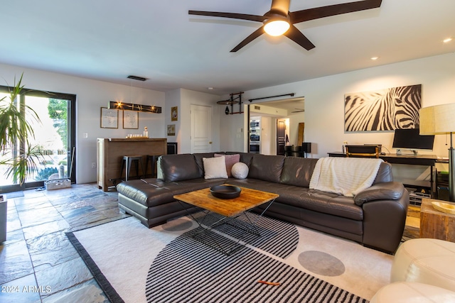 living room featuring ceiling fan and bar area