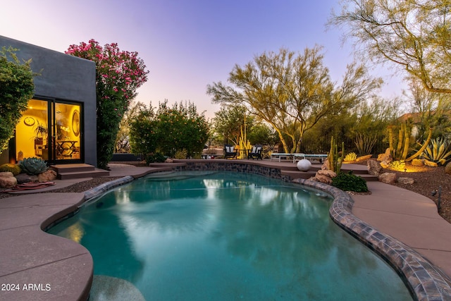 pool at dusk with a patio area