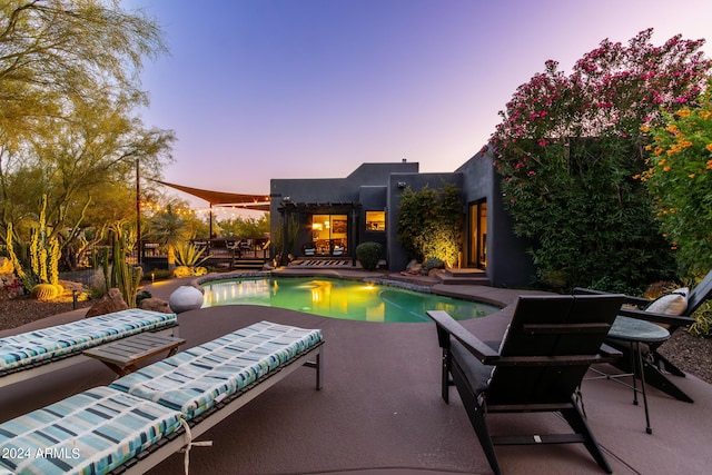 pool at dusk featuring a patio area