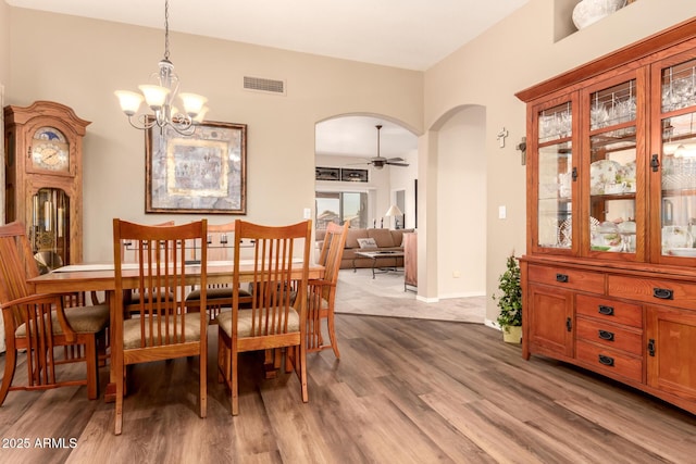 dining area featuring wood-type flooring and ceiling fan with notable chandelier