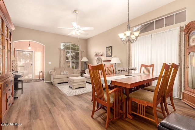 dining area with ceiling fan with notable chandelier and hardwood / wood-style flooring