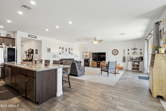 1135 E Barrus Dr, Casa Grande, AZ 85122 - kitchen with a breakfast bar area, a sink, ceiling fan, visible vents, and dark brown cabinets