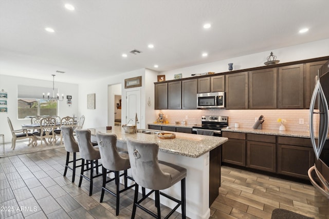 1135 E Barrus Dr, Casa Grande, AZ 85122 - kitchen with backsplash, a sink, a breakfast bar area, a center island with sink, and stainless steel appliances