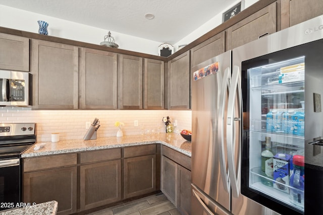 1135 E Barrus Dr, Casa Grande, AZ 85122 - kitchen with wood finish floors, a textured ceiling, decorative backsplash, light stone countertops, and appliances with stainless steel finishes