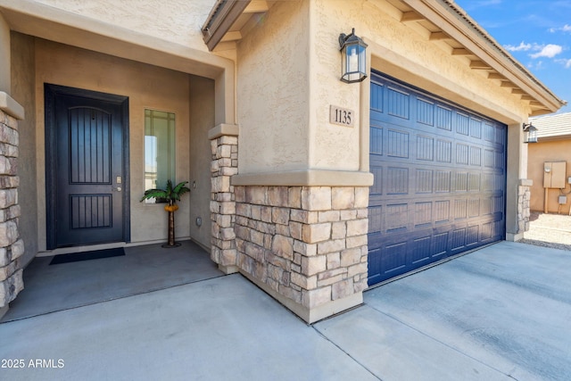 1135 E Barrus Dr, Casa Grande, AZ 85122 - view of exterior entry with stone siding, a garage, concrete driveway, and stucco siding