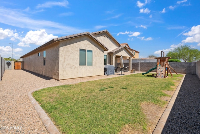 1135 E Barrus Dr, Casa Grande, AZ 85122 - back of house featuring a playground, a patio, a fenced backyard, a lawn, and stucco siding