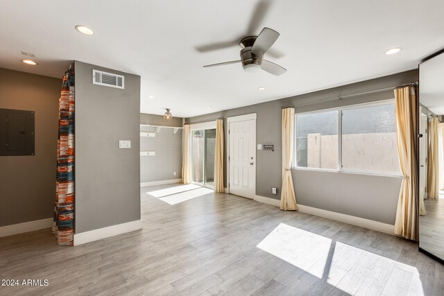 empty room with a wealth of natural light, electric panel, light hardwood / wood-style flooring, and ceiling fan