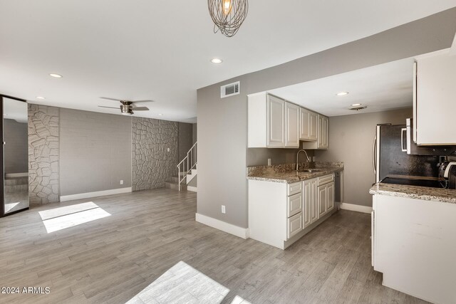 kitchen featuring ceiling fan, light stone countertops, sink, and light wood-type flooring