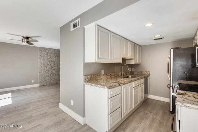 kitchen with light hardwood / wood-style floors, sink, light stone counters, and ceiling fan