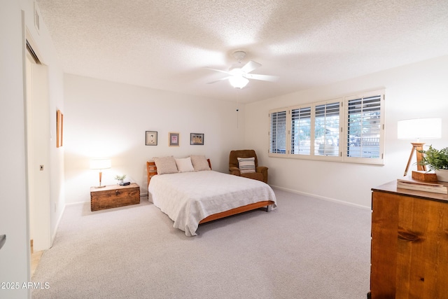 carpeted bedroom featuring ceiling fan and a textured ceiling