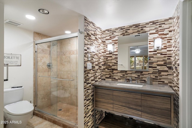 bathroom with tile patterned floors, vanity, tile walls, toilet, and a shower with shower door