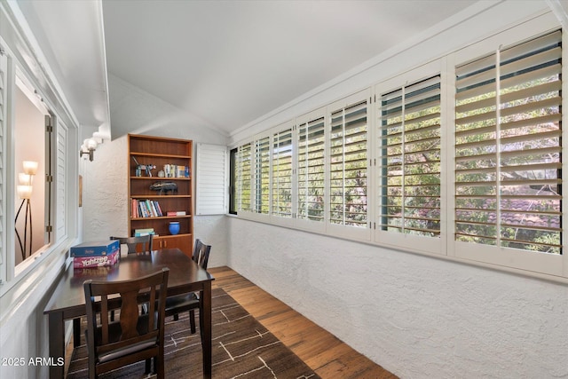 dining room featuring dark wood-type flooring, crown molding, and lofted ceiling