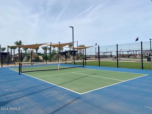 view of tennis court featuring a playground and basketball hoop