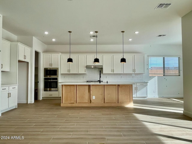 kitchen featuring white cabinetry, appliances with stainless steel finishes, an island with sink, and hanging light fixtures