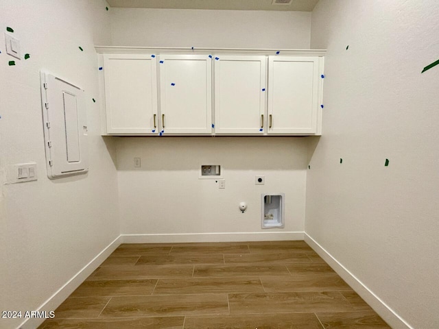 laundry room with hookup for a gas dryer, cabinets, electric panel, light hardwood / wood-style floors, and electric dryer hookup