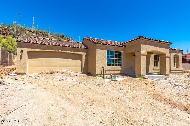 mediterranean / spanish home with a garage, a tile roof, and stucco siding