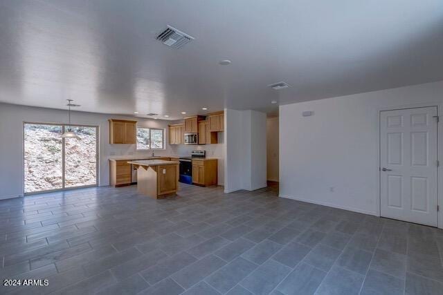 kitchen with visible vents, appliances with stainless steel finishes, a center island, hanging light fixtures, and light countertops