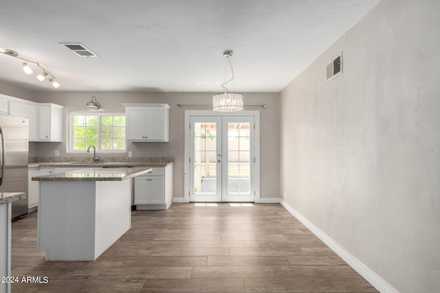 kitchen featuring a healthy amount of sunlight, a kitchen island, pendant lighting, and white cabinets