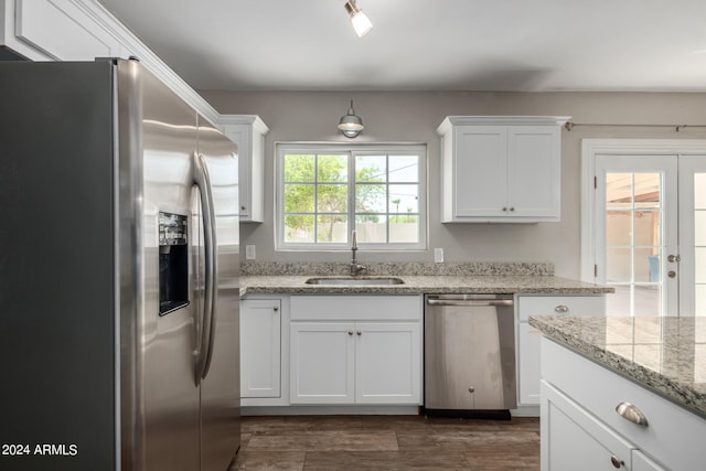 kitchen with white cabinets, appliances with stainless steel finishes, sink, and light stone counters