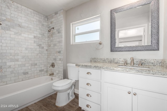 full bathroom with wood-type flooring, tiled shower / bath combo, vanity, and toilet